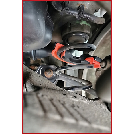 Nahaufnahme eines Stoßdämpfers mit Schraubzwinge. Ein schwarzes, gewundenes Federbein ist sichtbar, darüber ein roter und schwarzer Klemmmechanismus.